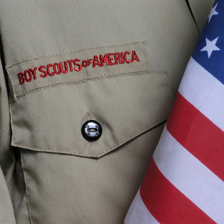 A close-up of a buttoned shirt pocket with 'Boy Scouts of America' embroidered above it