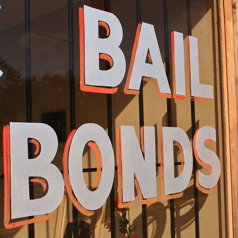 Image of a business' glass window with the words Bail Bonds painted on it.